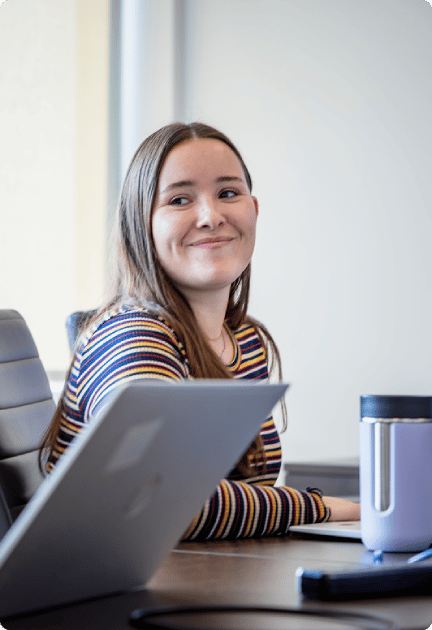 Femme assise à un bureau souriant à la caméra